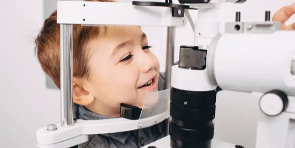 Young boy smiling during an eye exam at Moorfields Eye Hospital